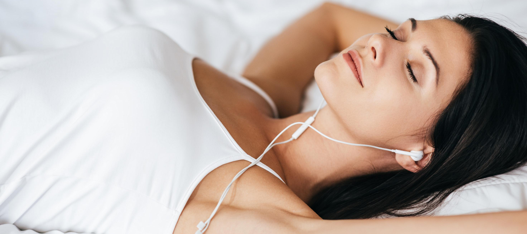 girl with headphones sleeping in a bed