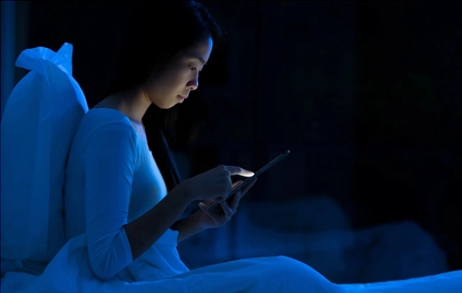 Woman in bed looking at her phone